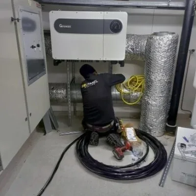Installatör monterar en växelriktare på väggen i ett teknikrum