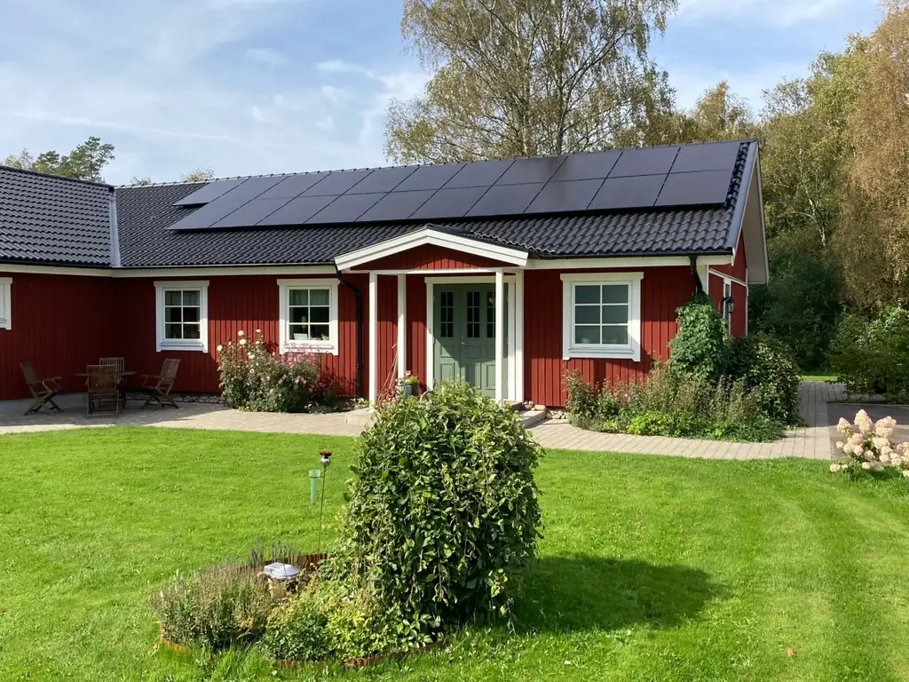 Röd villa med helsvarta solpaneler över hela takfallet